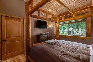 a bedroom with a large bed and a window at Aspen Cabin | Log Home | Hot Tub, Wood stove in Packwood