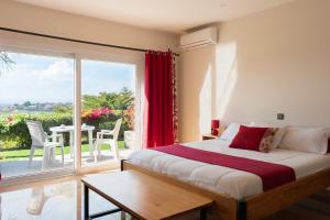 a bedroom with a bed and a balcony with a table at Somptua Garden Boutique Hôtel in Ivato +51 photos