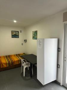a room with a table and a refrigerator and a bed at Quincho y hospedaje in Reconquista