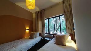 two beds in a room with a window at Boudha Breeze Suites 3bhk in Kathmandu