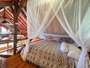 a bedroom with a bed with a mosquito net at Lakey Views Sumbawa in Huu