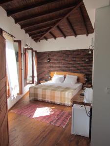 a bedroom with a bed and a brick wall at Amazon Petite Palace in Selcuk