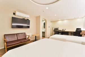 a hotel room with two beds and a couch and a television at Jamsil Tomgi Hotel in Seoul