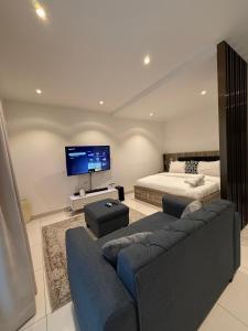 a living room with a couch and a bed and a television at The Snug Stay - Lennox in Accra