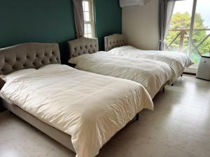 two beds with white sheets in a room with a window at Lei Toya in Sobetsu