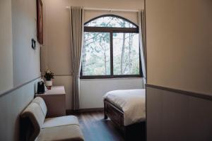 a small room with a bed and a window at Gia An Hotel Dalat in Da Lat