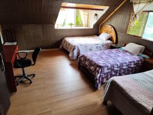 a room with two beds and a desk and a chair at Yanesh Haus habitaciones Oxapampa in San Antonio +3 photos