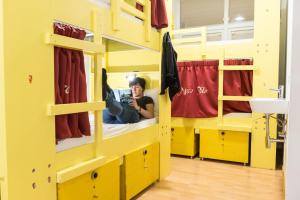 a man taking a picture in a yellow bunk room at Marco Polo Party Hostel in St. Julianʼs