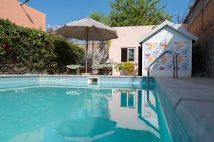 a swimming pool with an umbrella next to a house at Somptua Garden Boutique Hôtel in Ivato