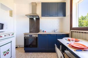 a kitchen with blue cabinets and a table with plates on it at Valras'Loc - Evasion Marine in Valras-Plage
