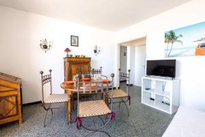a dining room with a table and chairs and a television at Valras'Loc - Evasion Marine in Valras-Plage