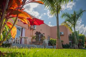a pink house with a palm tree and a red umbrella at Somptua Garden Boutique Hôtel in Ivato