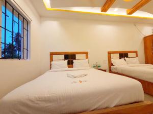 a bedroom with two beds with white sheets and a window at EESHA Beach View Stay - Near Temple and Beach in Rāmeswaram +26 photos