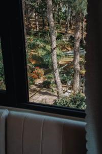 a window with a view of trees and flowers at Gia An Hotel Dalat in Da Lat