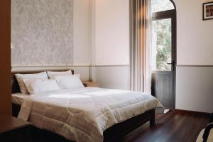 a bedroom with a large bed with a window at Gia An Hotel Dalat in Da Lat