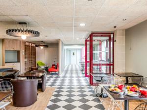 a restaurant with tables and chairs and a checkered floor at ibis Bordeaux Saint Emilion in Saint-Émilion