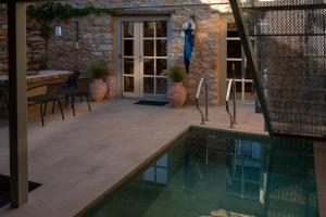 a swimming pool in a patio with a table and chairs at Olive Press 1816 in Riglia