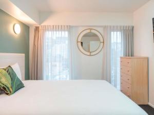 a bedroom with a white bed and a mirror at Mantra Central Wellington in Wellington