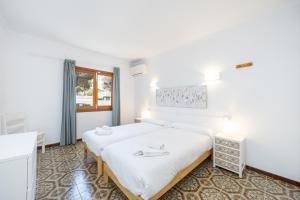 a bedroom with a large white bed and a window at Apartamentos MHM in Cala Ratjada