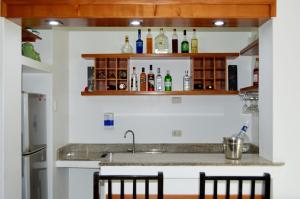 a kitchen with a sink and some bottles on shelves at HOTEL Casa cesar in Tumbes