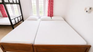 two beds in a room with two windows at K Cottage in Varkala +7 photos