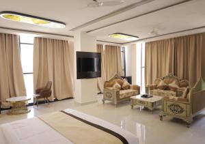 a living room with couches and a flat screen tv at Hotel Capital in Noida