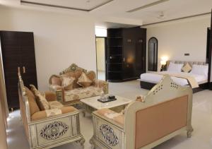 a living room with chairs and a couch and a bed at Hotel Capital in Noida