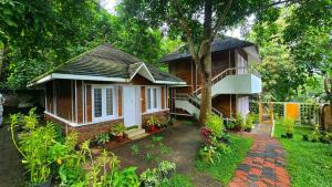 a small house with a tree in the yard at K Cottage in Varkala