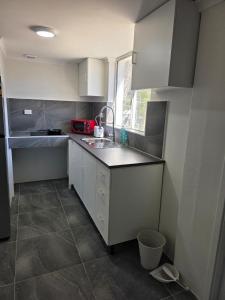a kitchen with white cabinets and a sink and a window at Sansa Farmhouse in Kelmscott