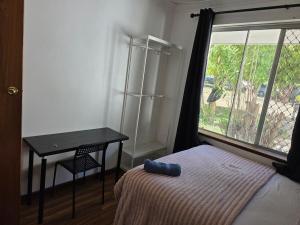a bedroom with a bed and a table and a window at Sansa Farmhouse in Kelmscott