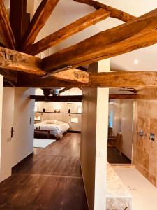 a large room with wooden ceilings and a bedroom at Maison Laroque & Spa in Bellefont-La Rauze