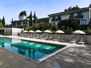 a swimming pool with chairs and umbrellas at Mercure Brignoles Golf de Barbaroux & Spa in Brignoles