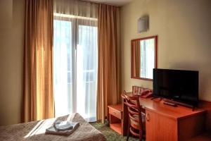 ein Hotelzimmer mit Bett, Fernseher und Kommode in der Unterkunft Dionis Hotel in Warna