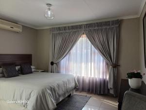 a bedroom with a bed and a large window at Duco self-catering in Nelspruit +19 photos