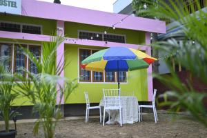 a table and chairs with a colorful umbrella in front of a house at The Backpackers Hostel in Guwahati