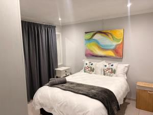 a bedroom with a bed with a painting on the wall at Local Roots in Pinetown