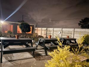 two picnic tables in front of a fence at night at Local Roots in Pinetown