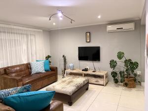 a living room with a couch and a flat screen tv at Local Roots in Pinetown