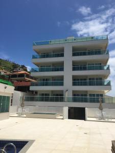 a white building with chairs in front of it at Apartamento em Arraial do Cabo in Arraial do Cabo