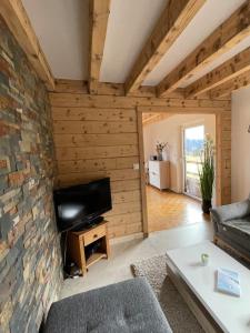 a living room with a stone wall and a tv at Chalet Les Balcons du Risoux in Bellefontaine