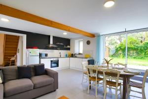 a living room with a couch and a table and a kitchen at Chez Manie Et Mablot in Créances