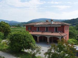 a red house with a mountain in the background at Bosco Romagno in Cividale del Friuli