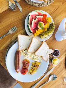 a plate of food with sandwiches and fruit on a table at Cozy Bay Hotel in Arugam Bay