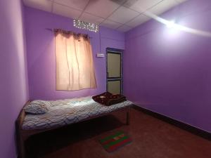 a purple room with a bed and a window at Pranoti guest house in Dibrugarh