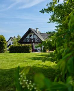 a house on a lawn with green grass and trees at Nadmorska Osada in Łeba
