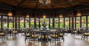a dining room with tables and chairs and windows at The Peninsula Manila in Manila