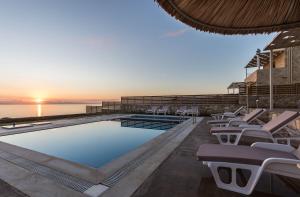 a swimming pool with lounge chairs and the ocean at Villa Lefkopetra in Triopetra