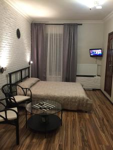 a bedroom with a bed and a table and a tv at Guest House "Nevsky 6" in Saint Petersburg