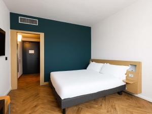 a bedroom with a white bed and a blue wall at Novotel Caserta Sud in Caserta