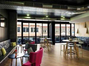 a restaurant with tables and chairs and windows at ibis Adelaide in Adelaide